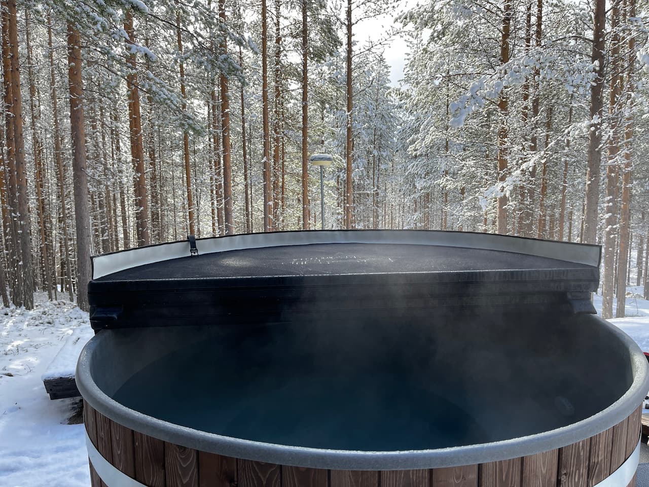 Höyryävä palju lumisessa metsässä Kettukummun pihalla